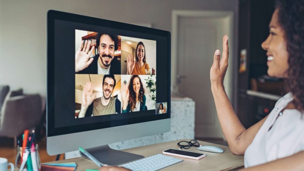 Photo of woman waving at virtual coworkers for virtual meetings